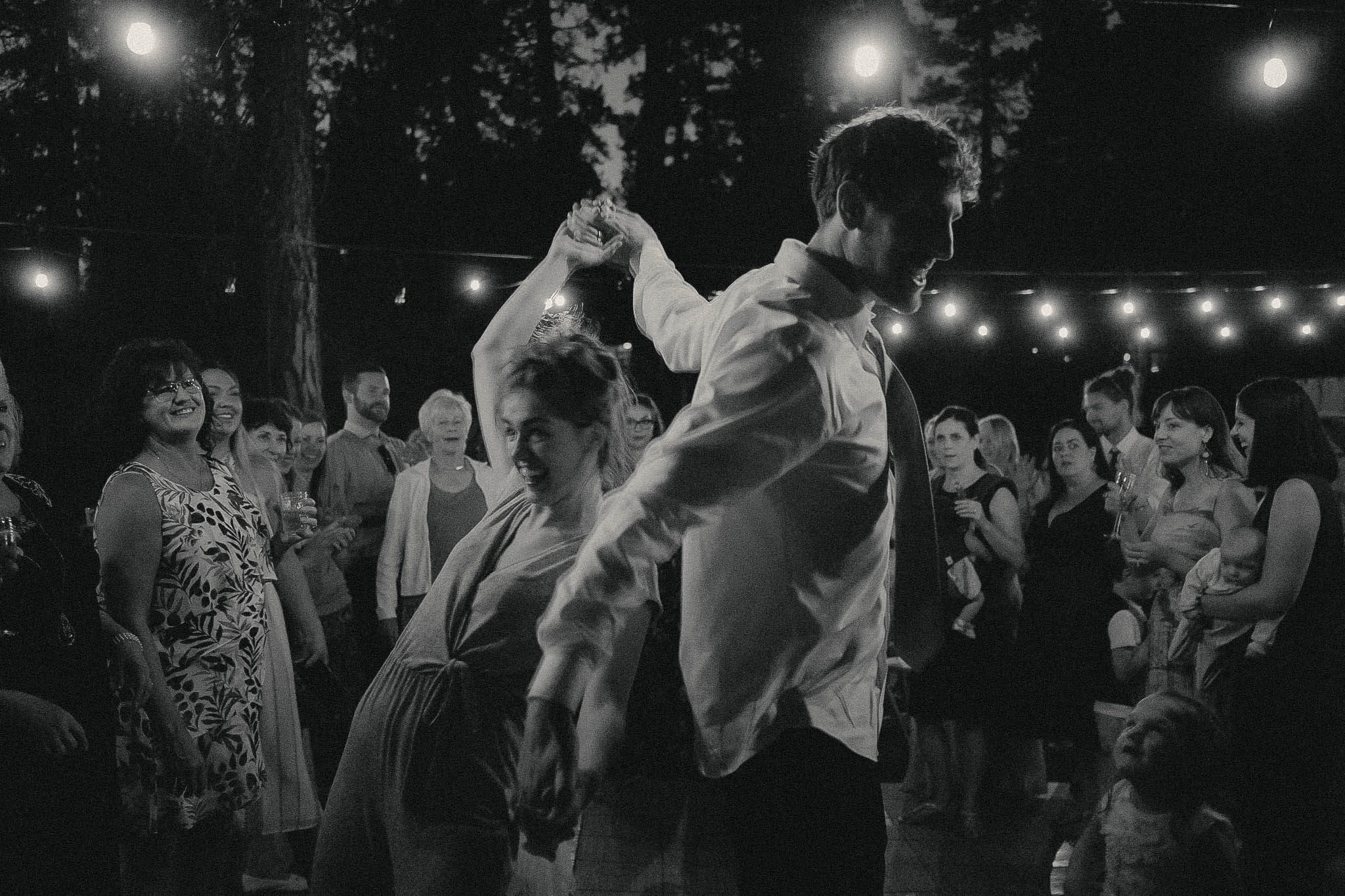 The couple dancing under string lights at the reception